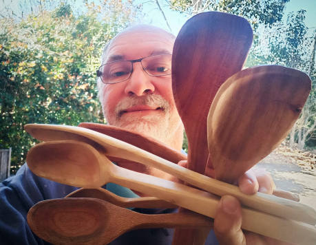 man holding many wooden cooking spoons